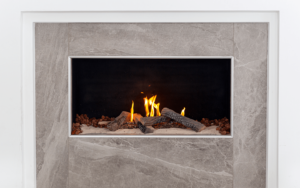 Foto de frente de Chimenea de gas adornada con madera decorativa y paneles de mármol a los lados.